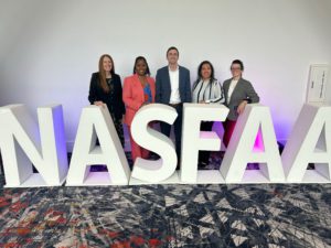 The Financial Aid Services team in a group photo in front of large letters spelling out NASFAA. 